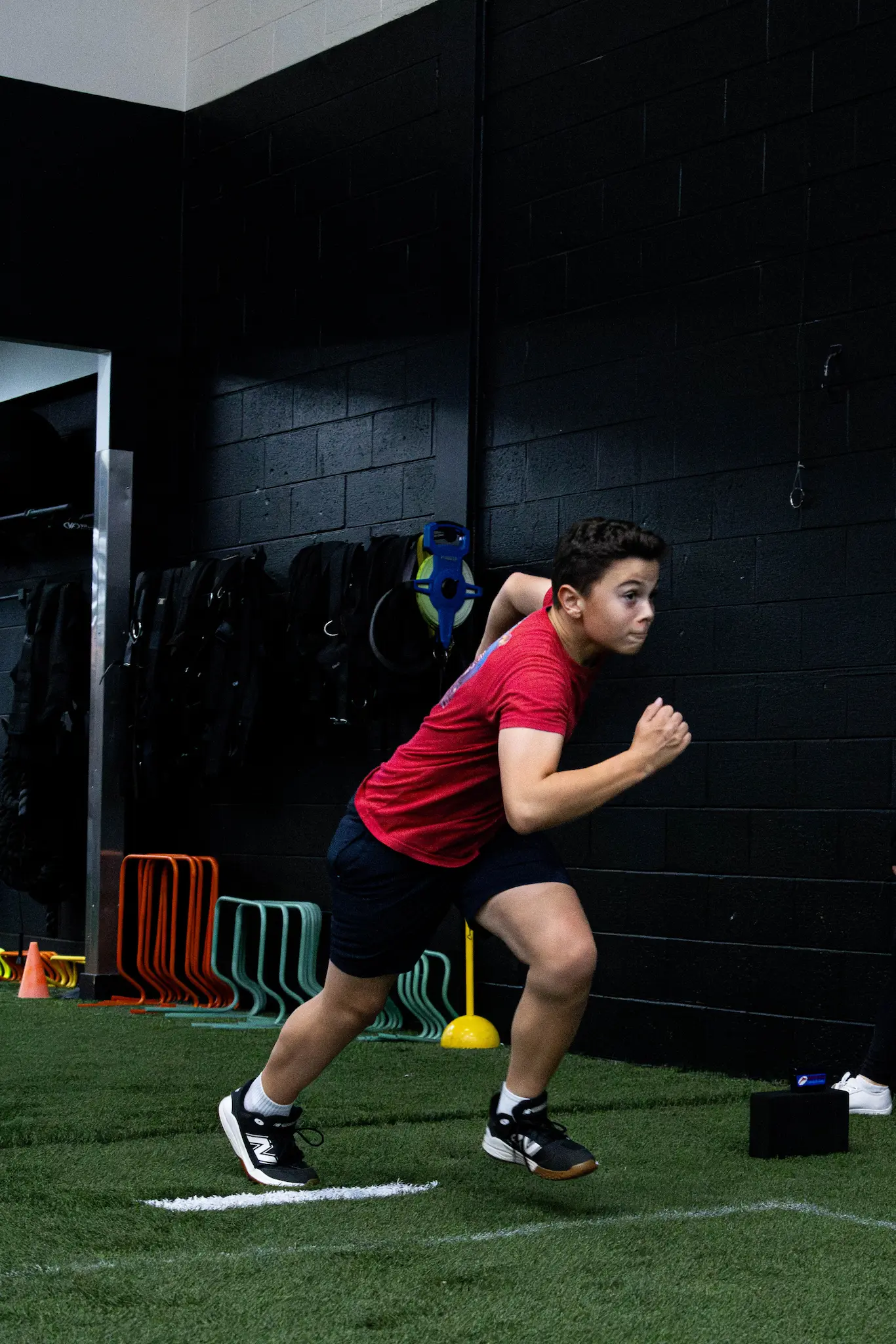 An athlete in a starting stance, likely part of an indoor speed and agility training session