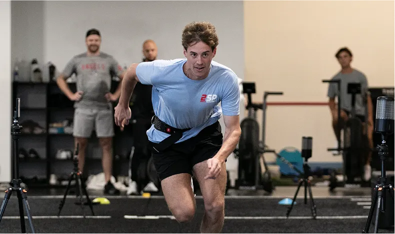 An athlete at a sports performance facility using a resisted sprint training band for explosive speed and acceleration drills. This type of speed testing is commonly conducted at specialized training centers.