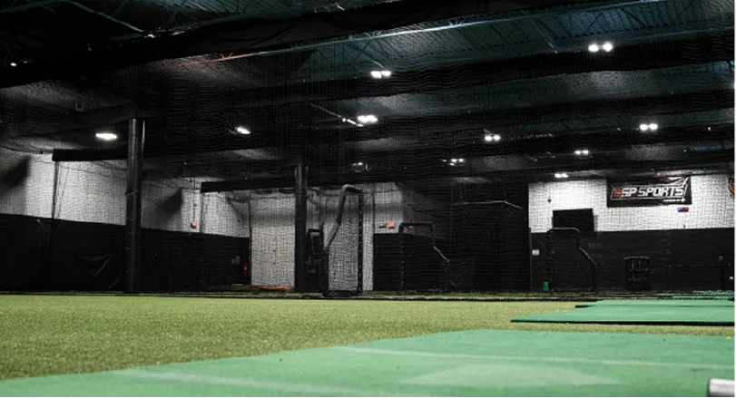 Indoor sports facility equipped with artificial turf, batting cages, and protective netting, which is widely used for baseball and softball training.