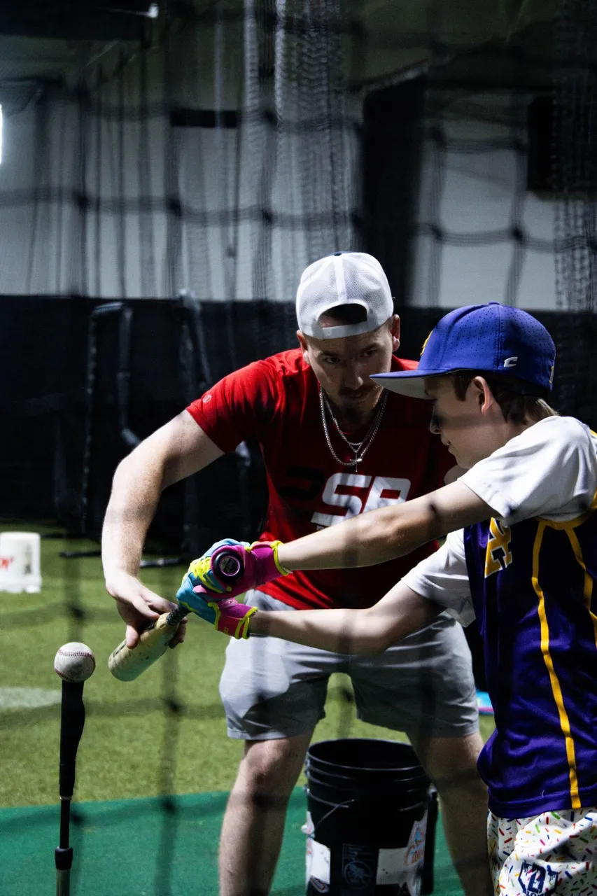 A dedicated one-on-one batting lesson at the 2SP Fieldhouse in Metro Detroit. The facility offers private sessions, small group training, and cage rentals for youth athletes