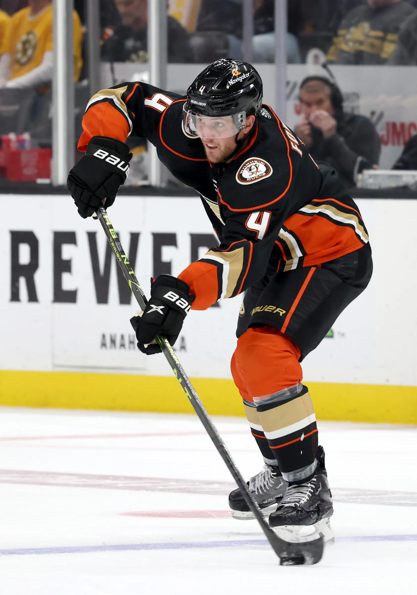 Anaheim Ducks hockey player in black and orange uniform controlling puck on ice with stick.