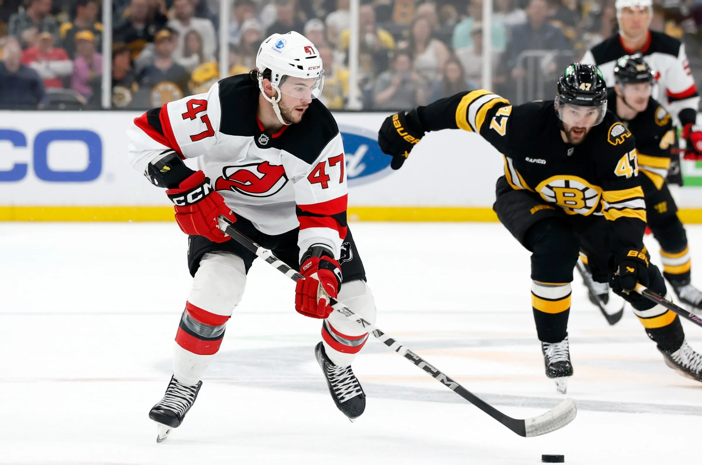 Two ice hockey players with number 47 compete for puck on the ice during a game.