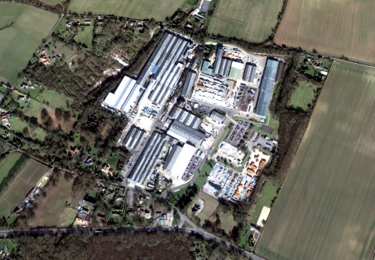 Aerial view of a large industrial complex surrounded by fields and scattered residential houses.