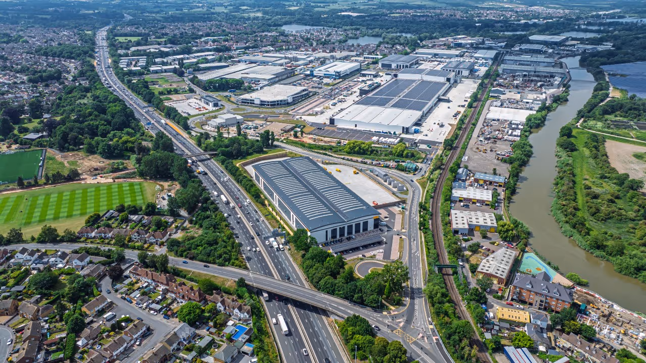 Red and black forklift carrying pallet near open warehouse door outside industrial building.