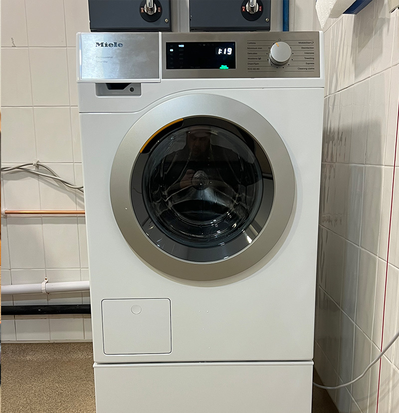 Front-loading Miele professional washing machine with digital display showing 1:19 remaining wash time.