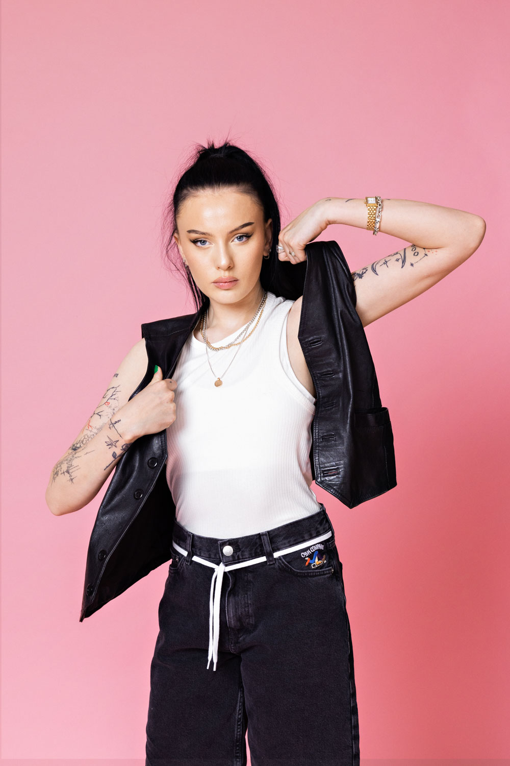 En ung kvinne poserer inne i et fotostudio med rosa bakgrunn