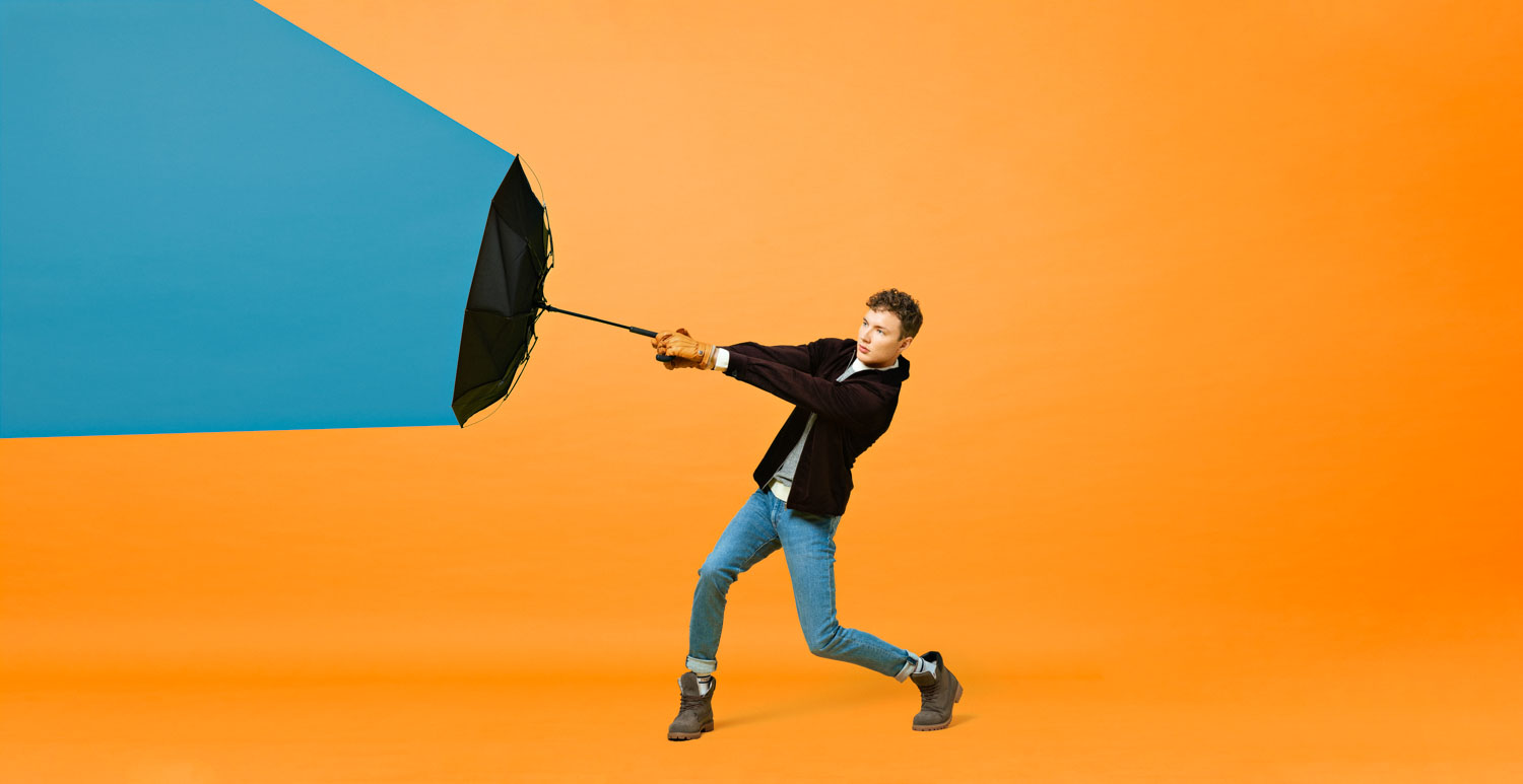 En mann holder opp en paraply i et fargerikt fotostudio