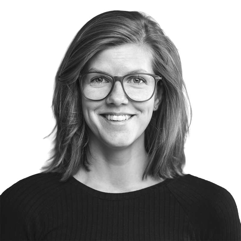 Ansattbilde i svart hvitt av en smilende kvinne med briller