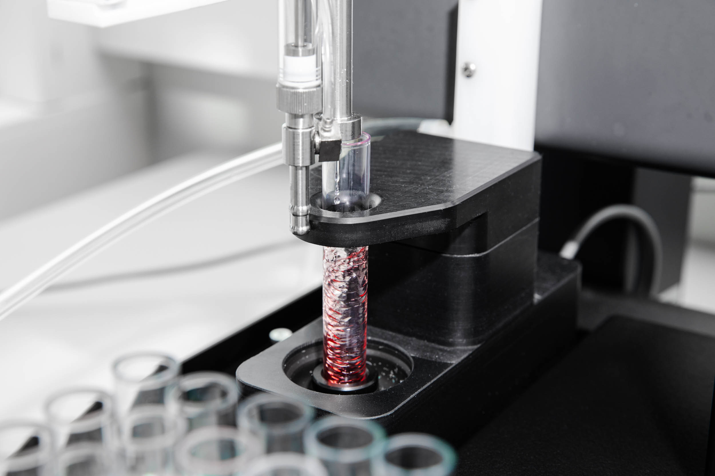 Nærbilde av en labmaskin som snurrer på et rødlig væskeinnhold