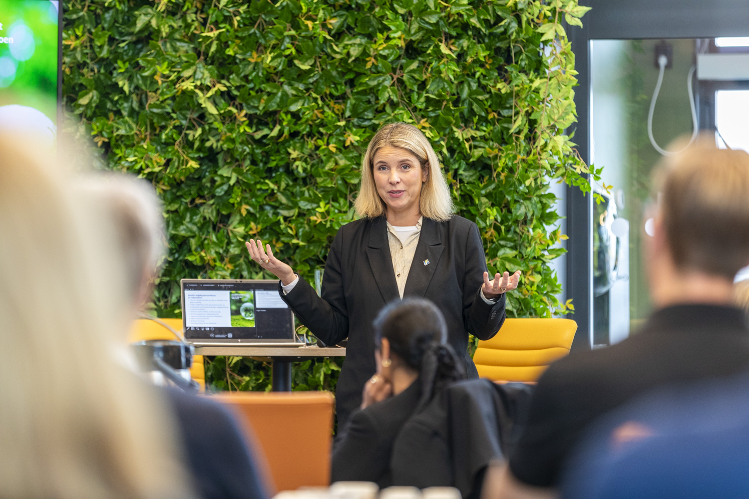 En kvinne står i et møterom og presenterer