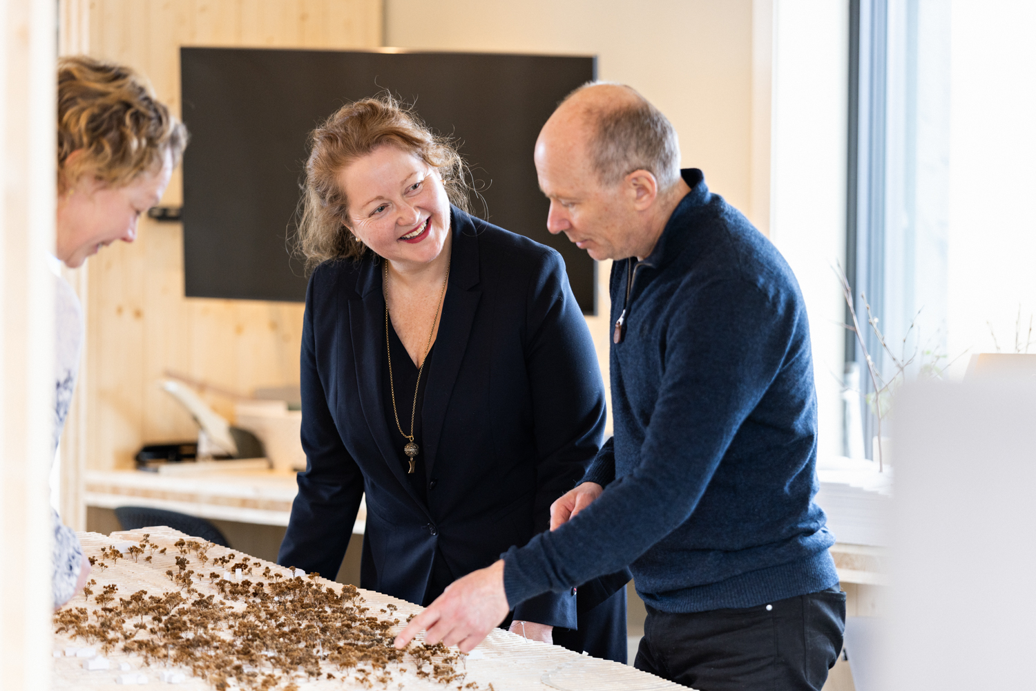 Tre personer peker på en miniatyr-installasjon