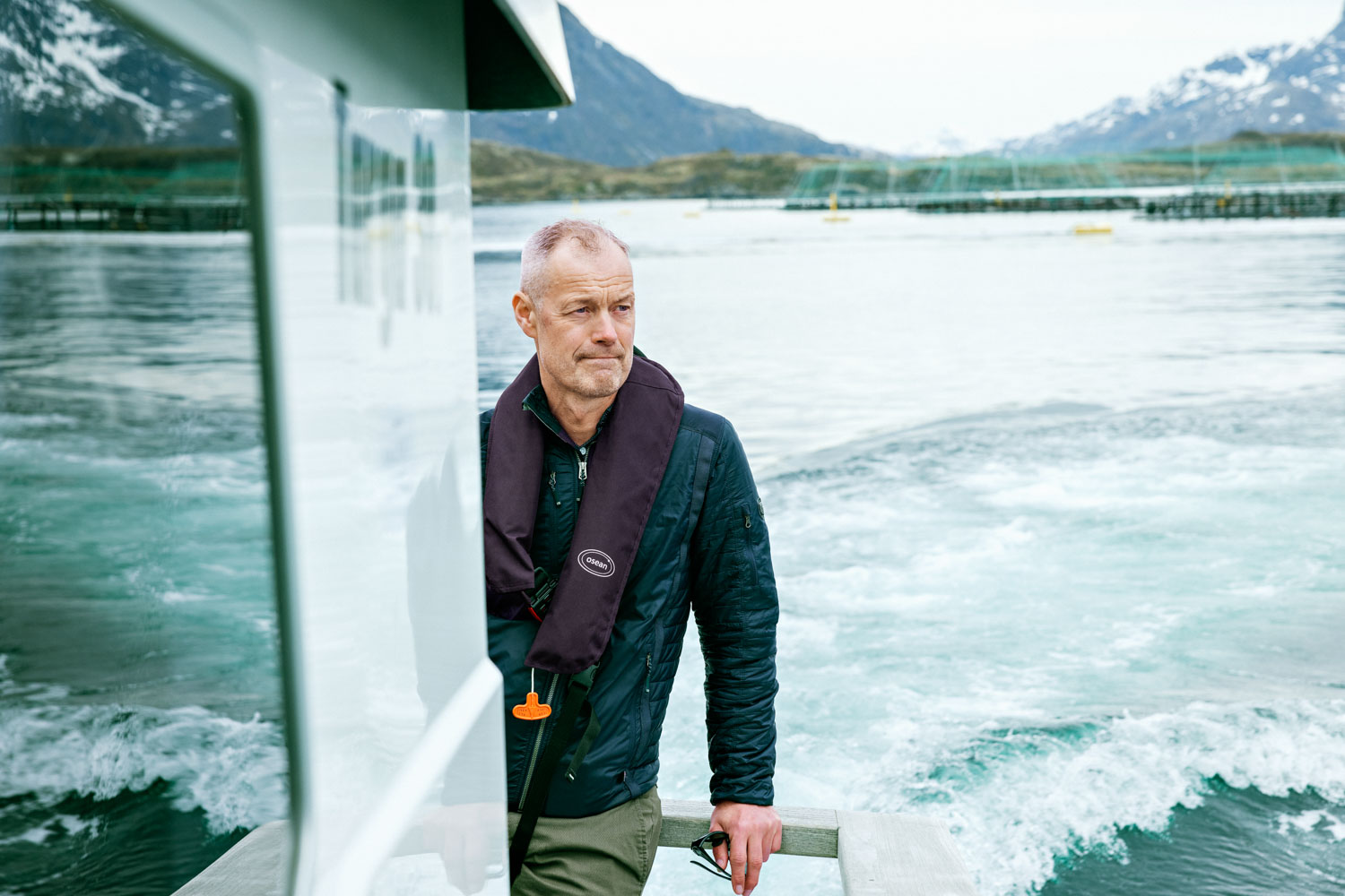 En mann kjører en båt langs merder ute på havet