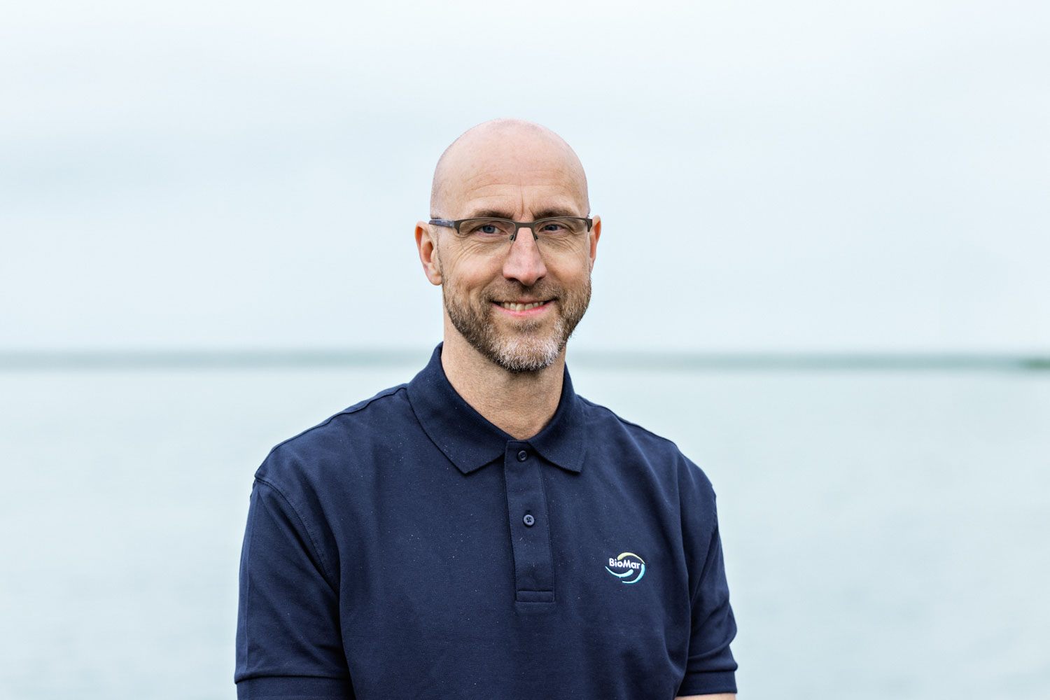 Portbilde av en mann som ser i kamera og smiler foran havet