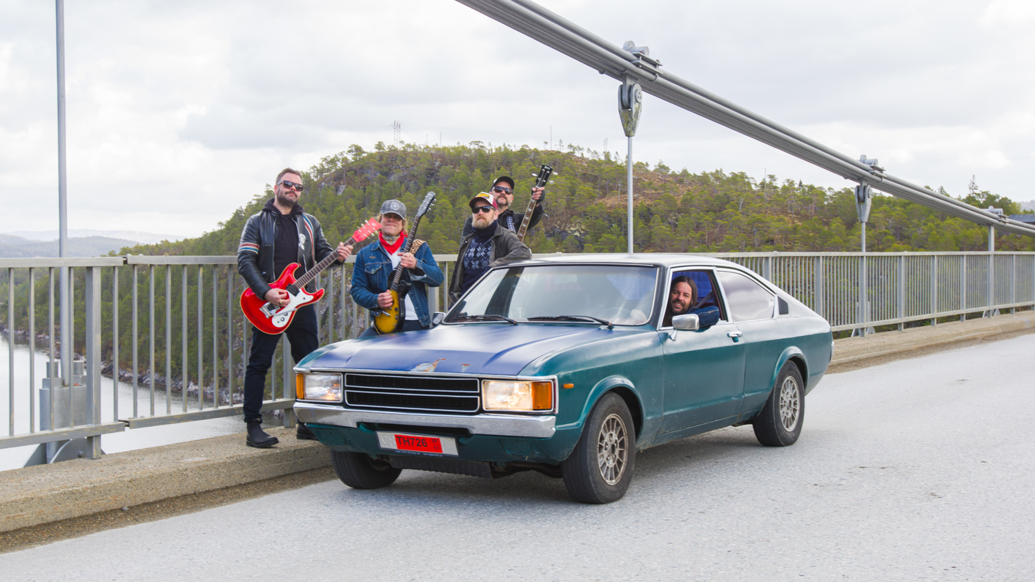 Bandbilde av rockebandet Nullskattesnylterne, tatt ute på en bro sammen med en bil