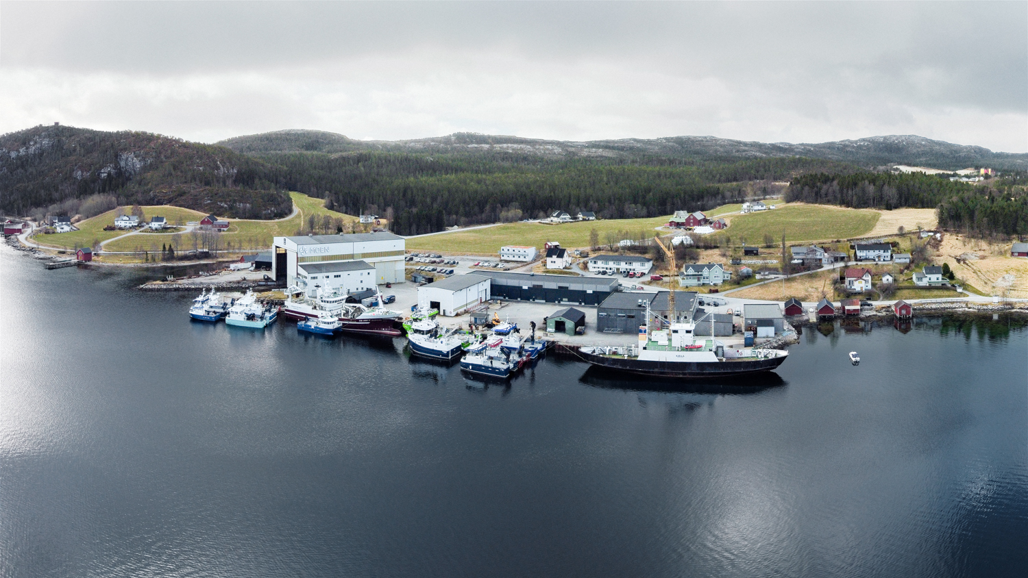 Dronefoto av en havn med flere båter i ulike størrelser.