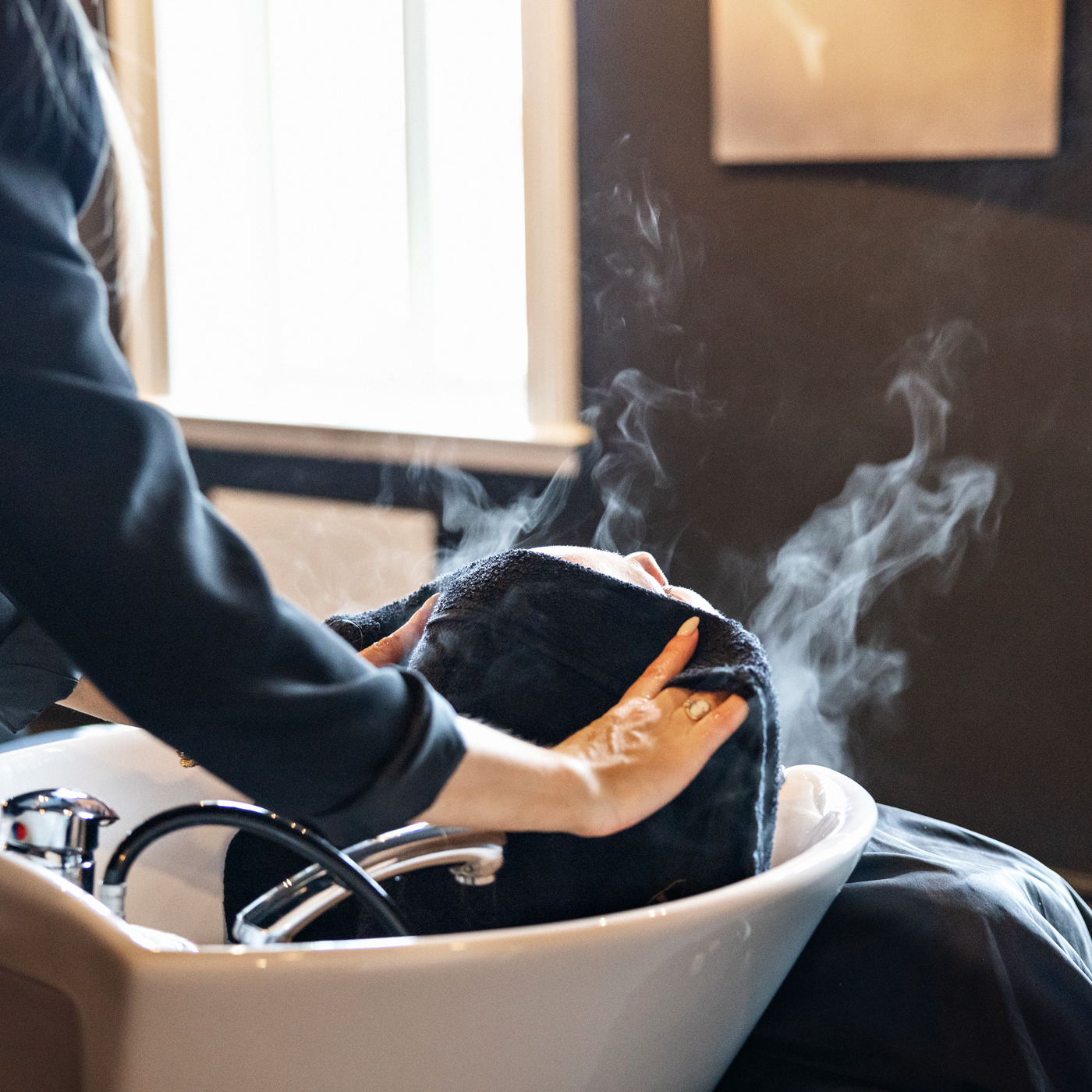 Nærbilde fra en kunde hos Palé 3 som får et varmt håndkle over hodet.