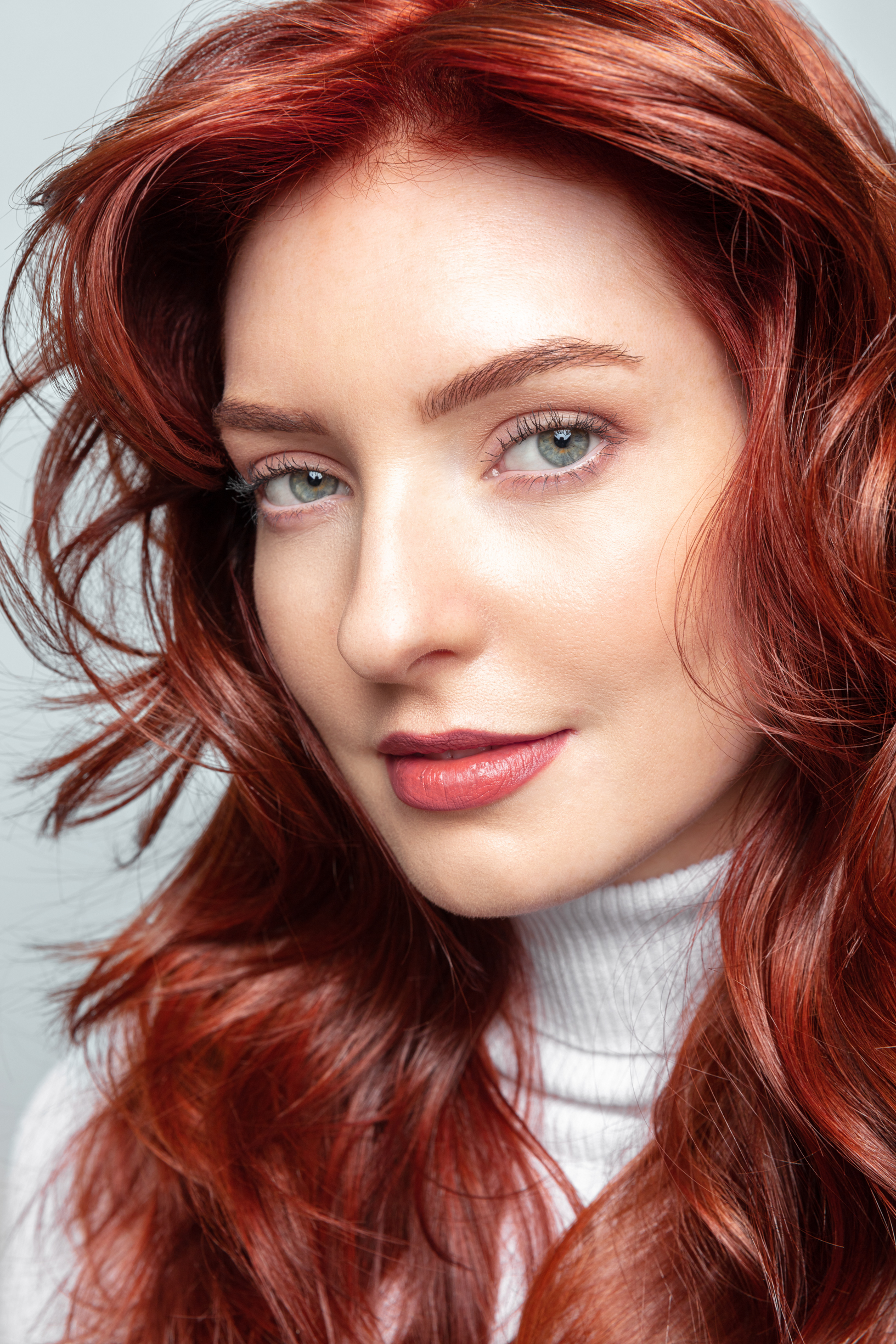 Nærbilde av en ung kvinne med langt rødt hår som har blikket mot kamera