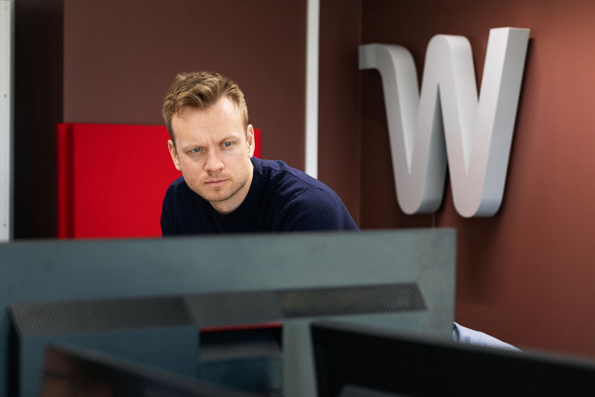 En mann står og presenterer i et moderne kontorlandskap