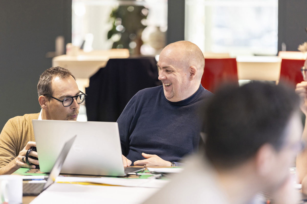 Tre menn sitter og jobber i et moderne kontorlandskap