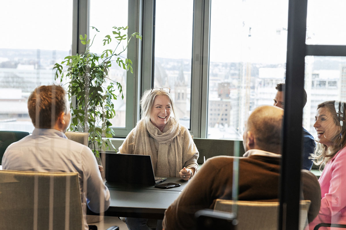 Fire personer sitter og jobber ved et vindu
