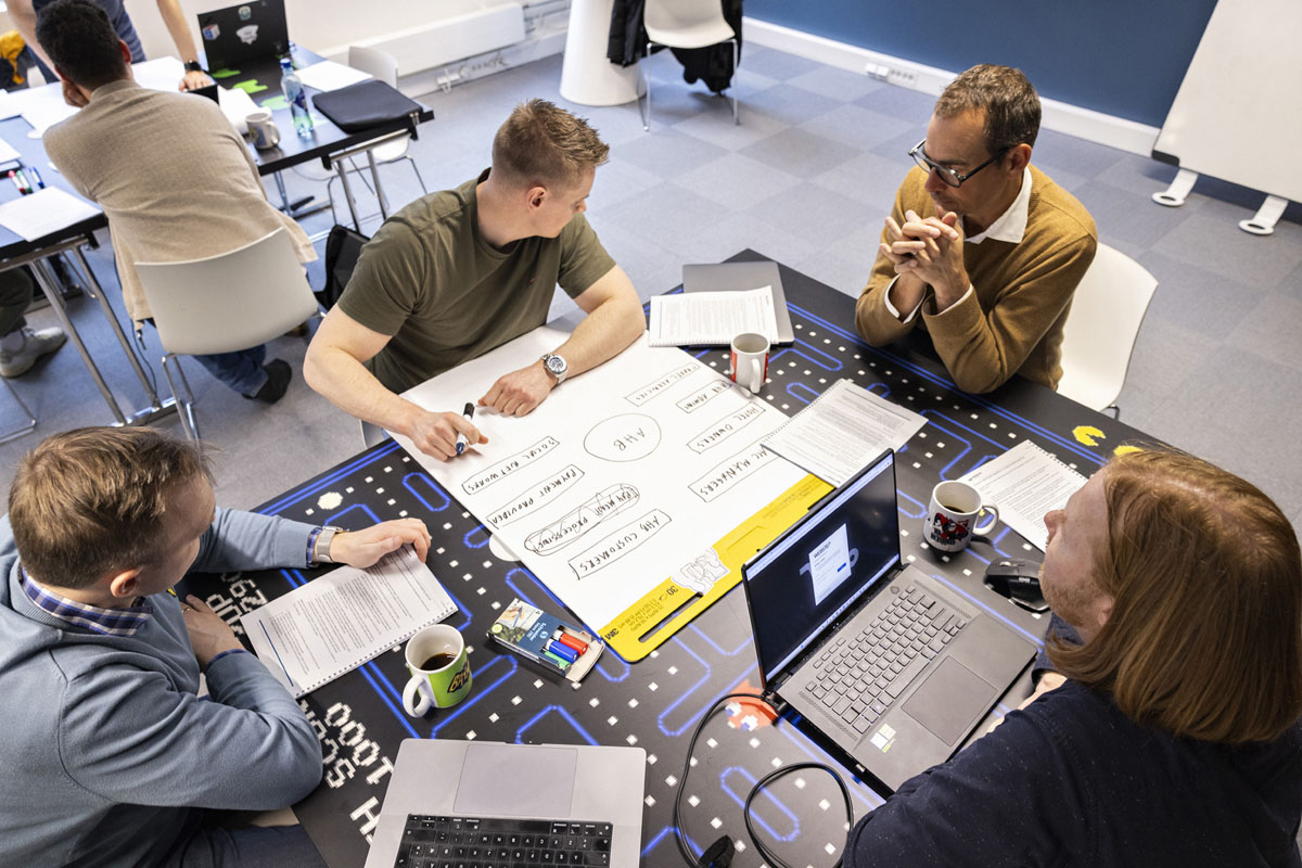 En liten gruppe mennesker sitter rundt et bord og jobber