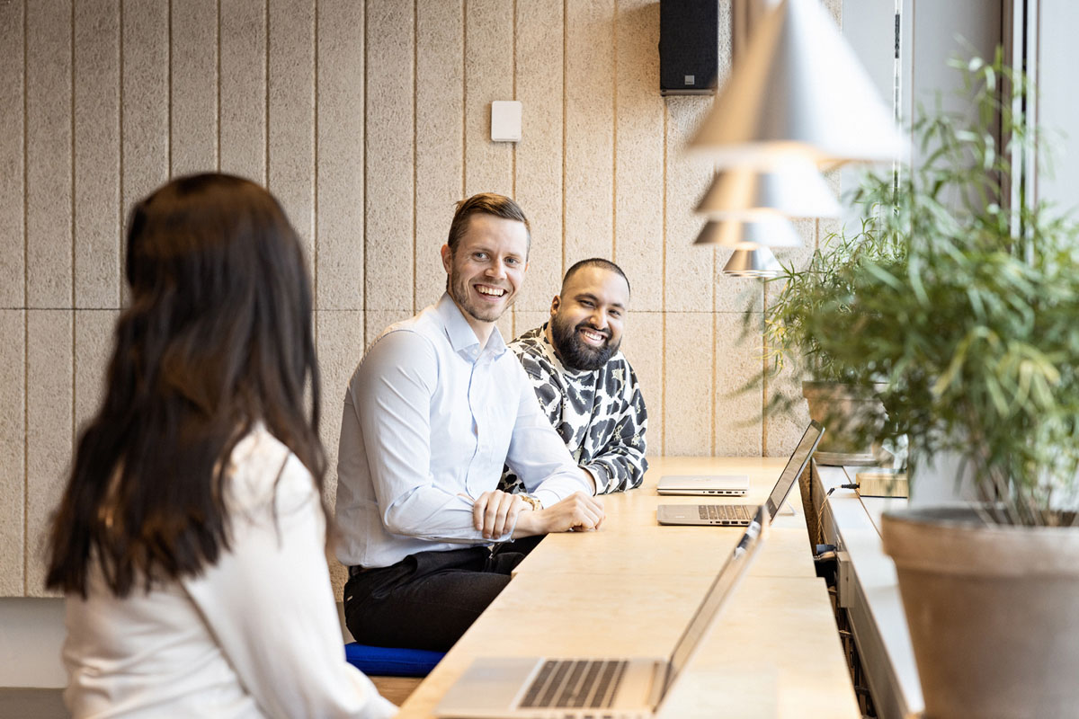 Tre personer sitter og jobber ved et vindu