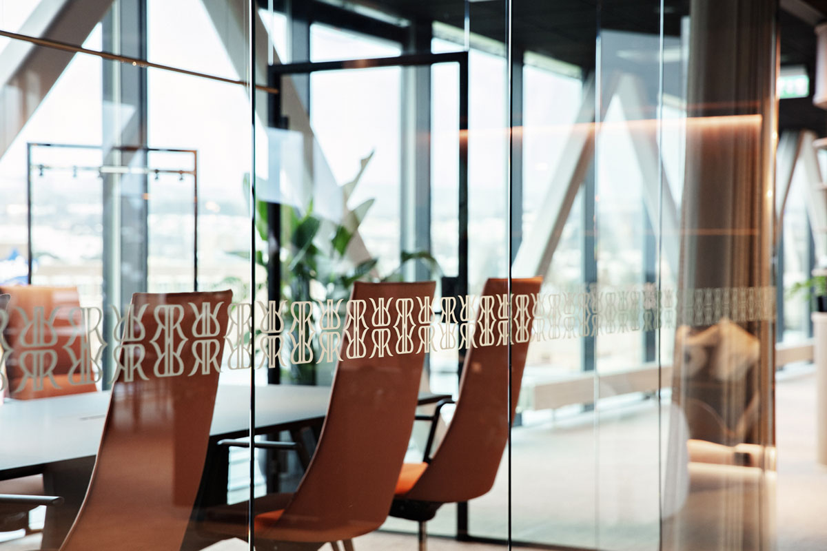 Møterom med glassvegger midt i et moderne kontorlandskap