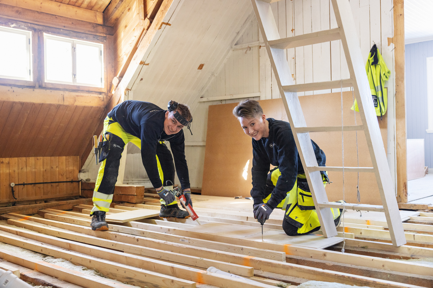 To tømrere jobber sammen i hus under konstruksjon