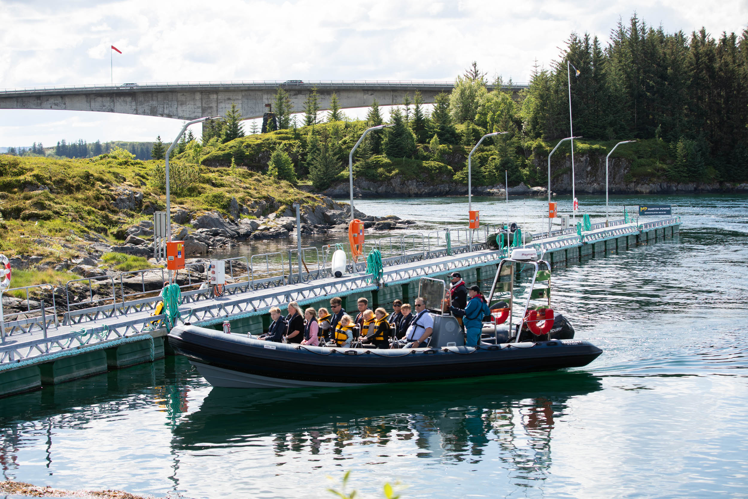 En rib med en gruppe mennesker kjører nærme en brygge