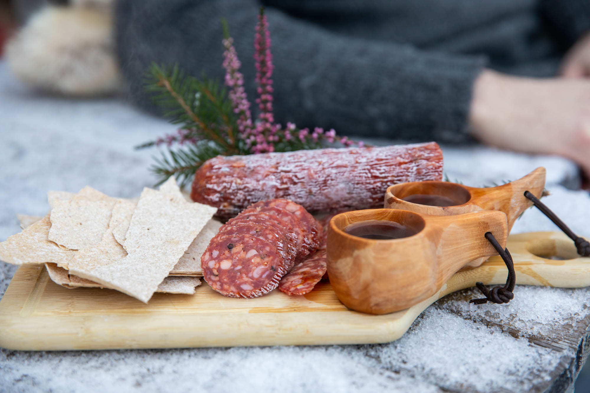 Nærbilde av en spekefjøl med spekemat, flatbrød og en kaffekopp, tatt ute på vinteren