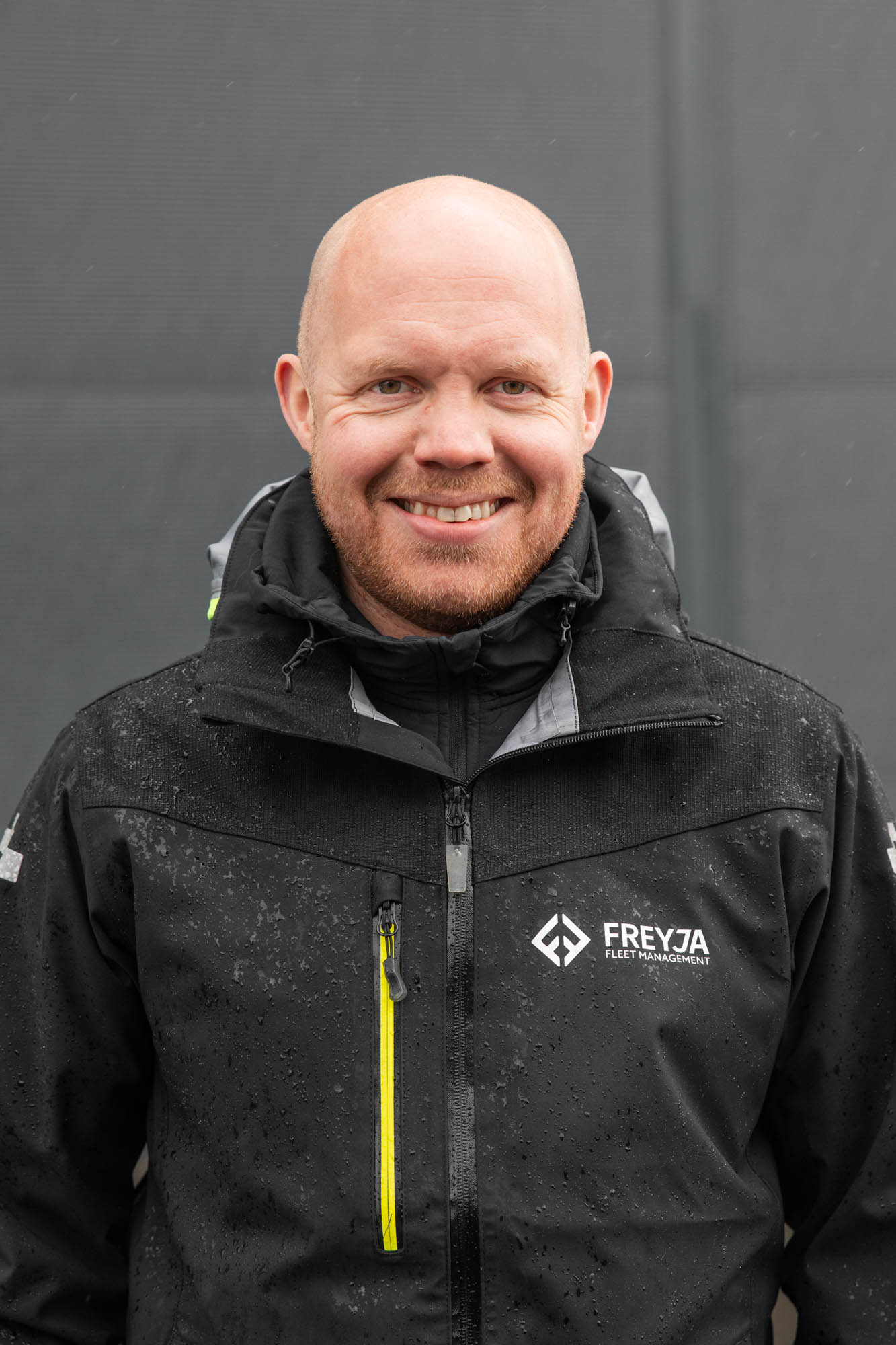 portrettbilde av en mann som står ute i jakke med logo 