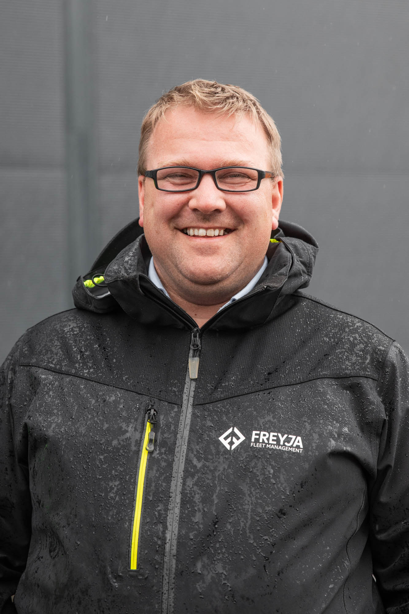 portrettbilde av en mann som står ute i jakke med logo 