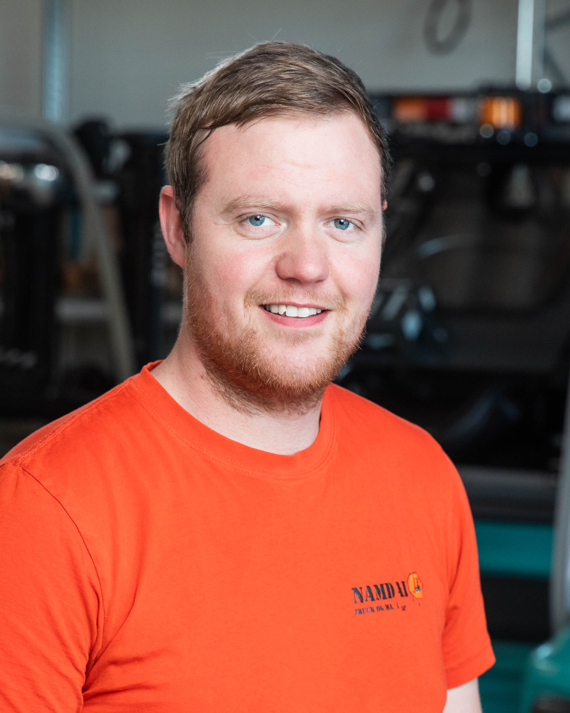 Ansattfoto av en mann som smiler mot kamera inne i et verksted