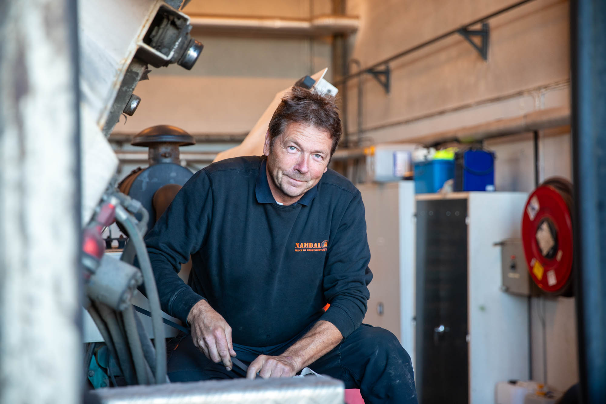 En mann ser i kamera mens han jobber i et verksted