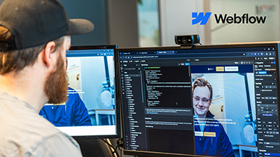 En mann bygger opp en nettside, på skjermen hans vises koding og nettsidens layout