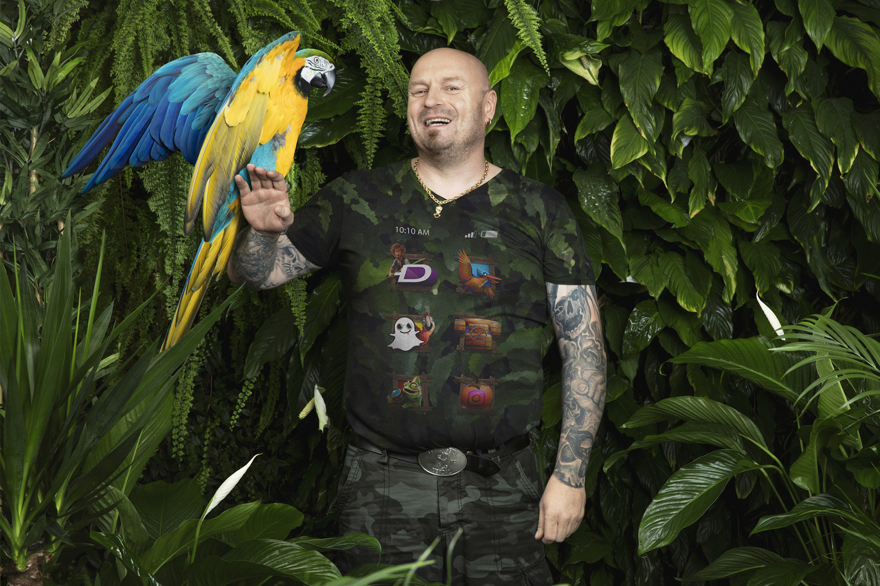 en mann står med en papegøye foran en grønn vegg