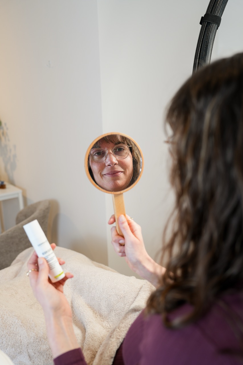 vrouw kijkt in de spiegel naar haar huid