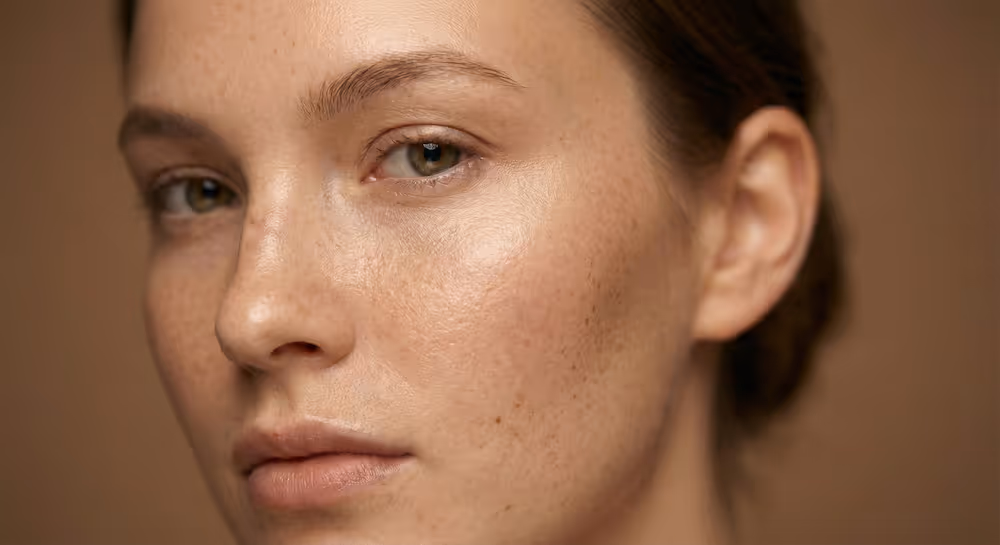Nahaufnahme des Gesichts einer Frau mit glatter, strahlender Haut und verfeinerten Poren.