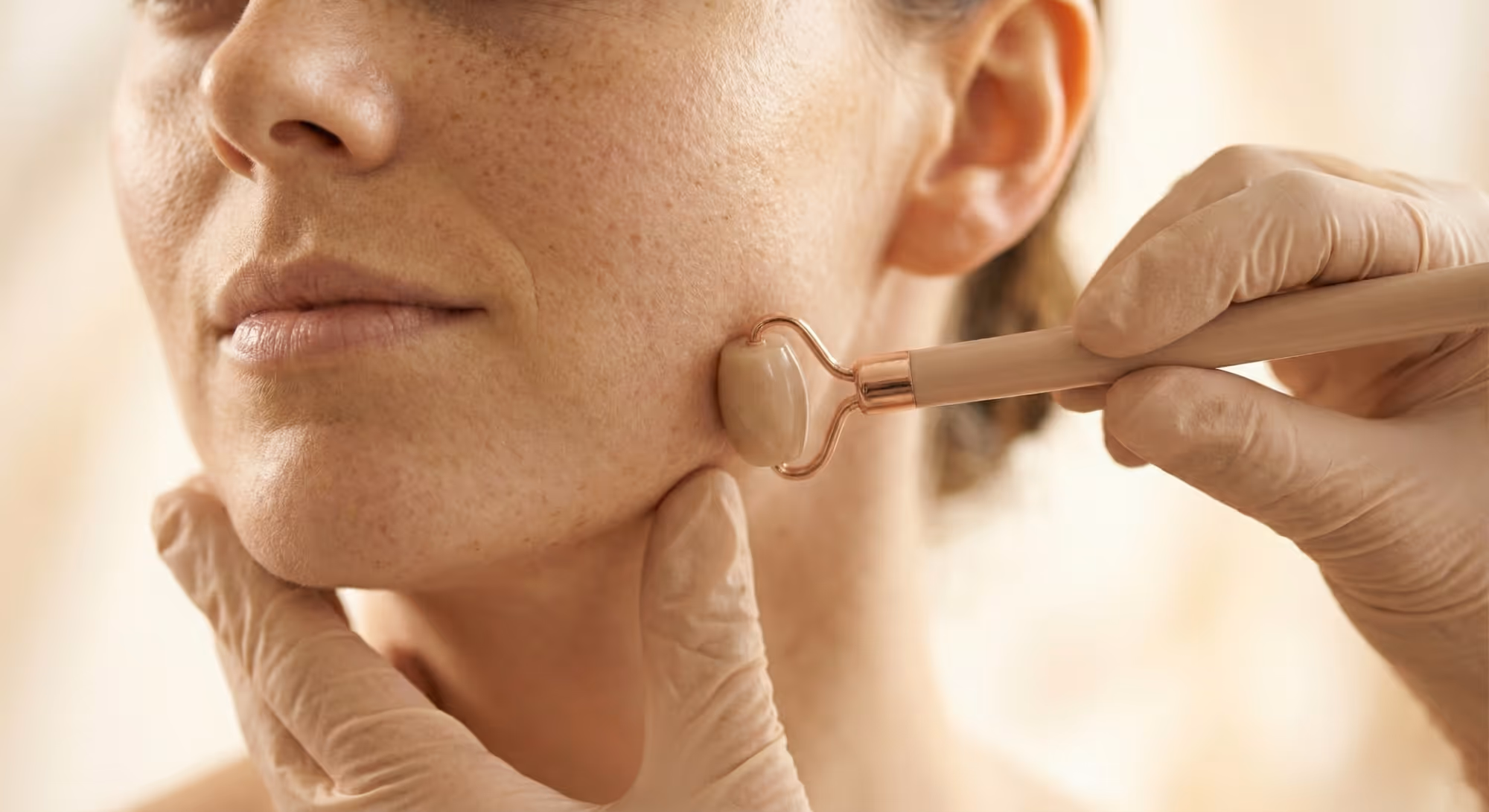 Behandschuhte Hände eines Behandlers massieren den Kaumuskel (Masseter) zur Beurteilung von Verspannungen.