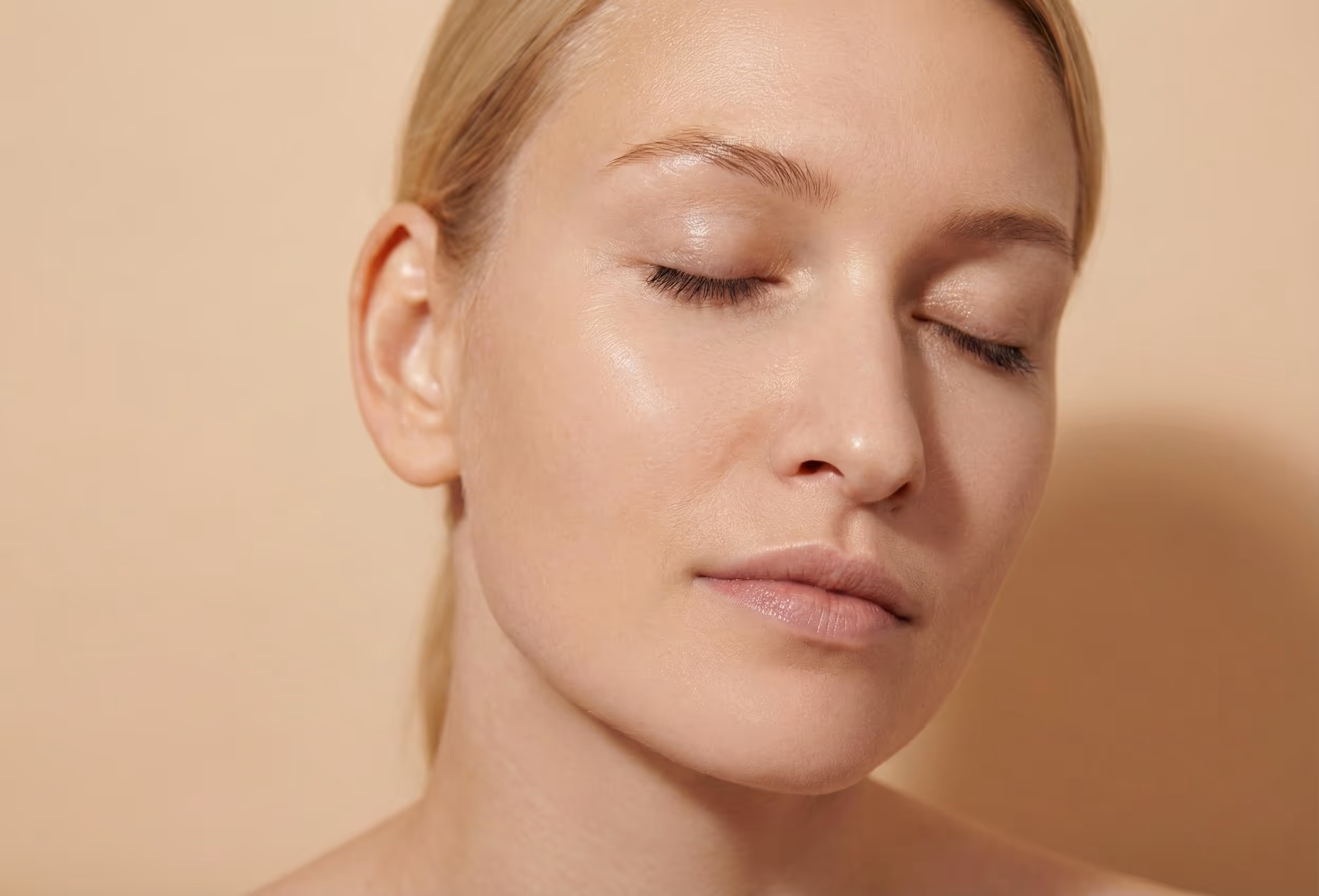 Nahaufnahme des Gesichts einer Frau mit glatter, strahlender Haut und verfeinerten Poren.