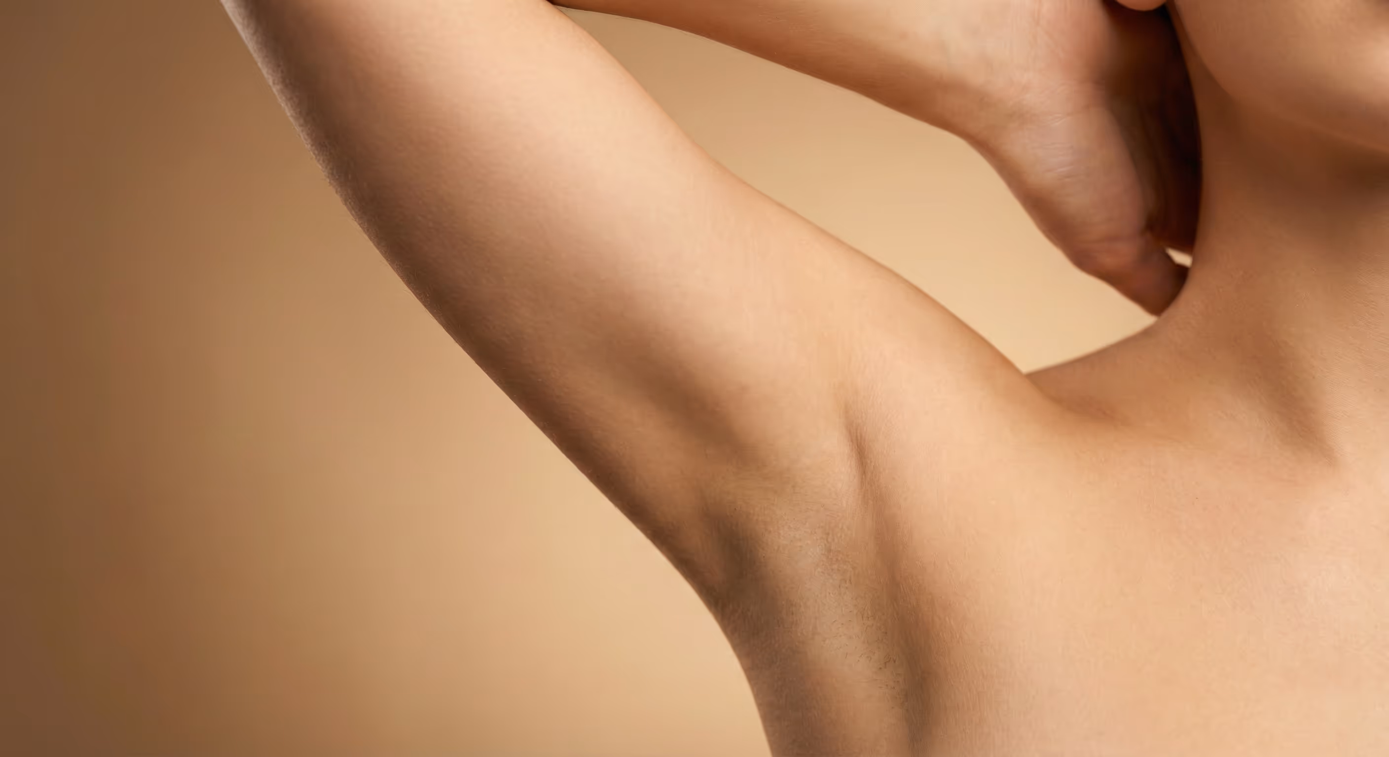 Nahaufnahme von glatter, gepflegter Achselhaut vor einem weichen, neutralen Hintergrund.