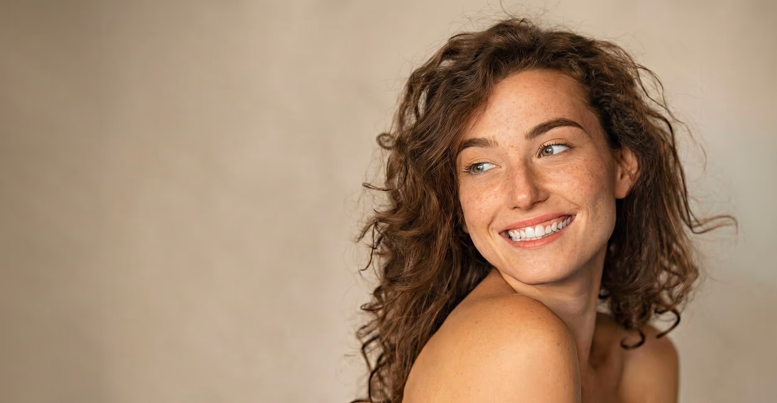 Porträt einer nach oben blickenden Frau mit weicher, strahlender Haut, geeignet als Header-Hintergrund für Kliniken