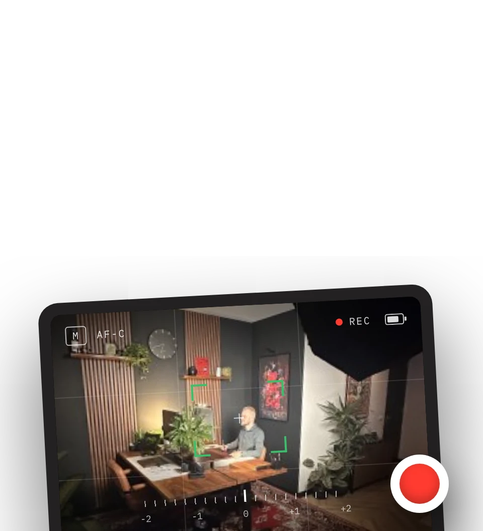 A camera screen showing the studio set with focus box and record button