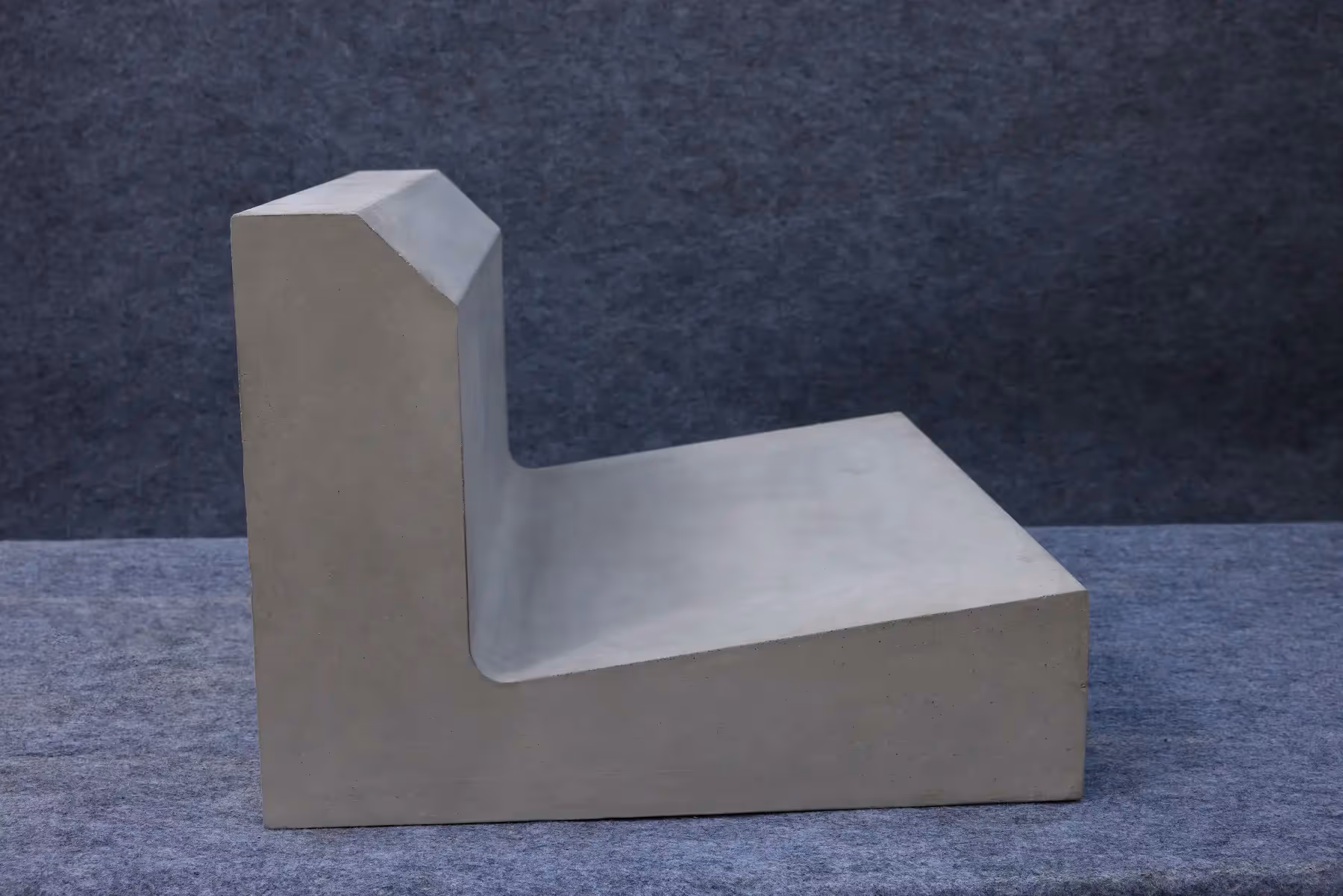 Precast L-shaped kerb with drain in grey concrete, side view showing the upright kerb and sloped channel base