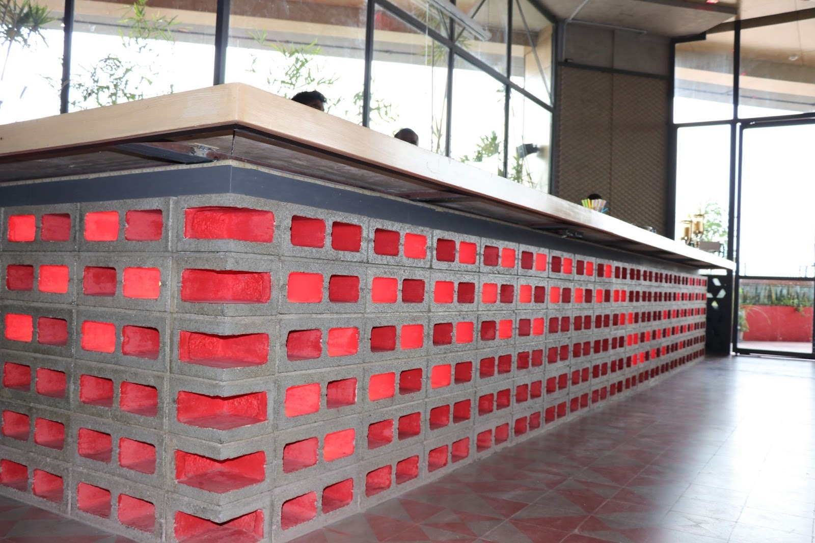 6-inch grey concrete Hollow Blocks forming a perforated counter front in a restaurant, with red backlit cavities