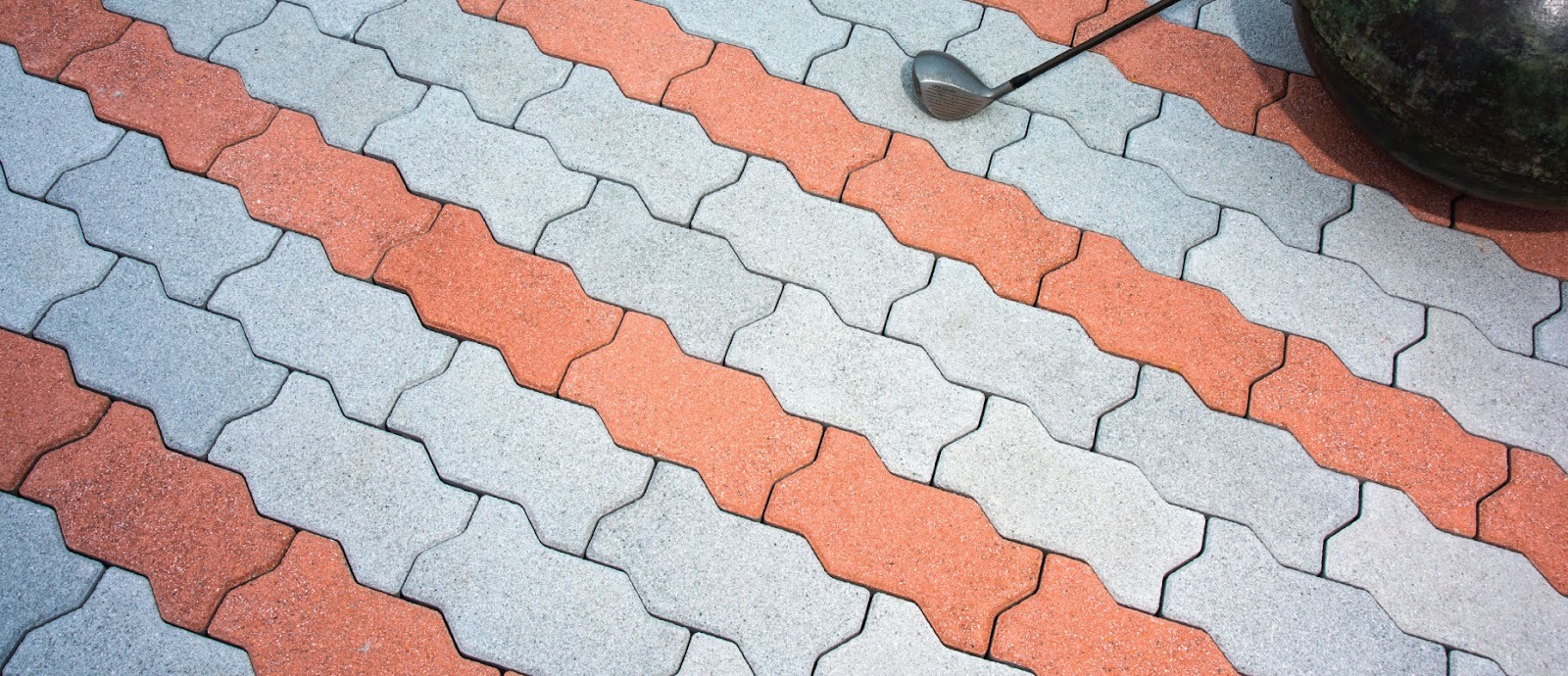 Zigzag interlocking pavers in grey with diagonal bands of red, laid in a striped pattern