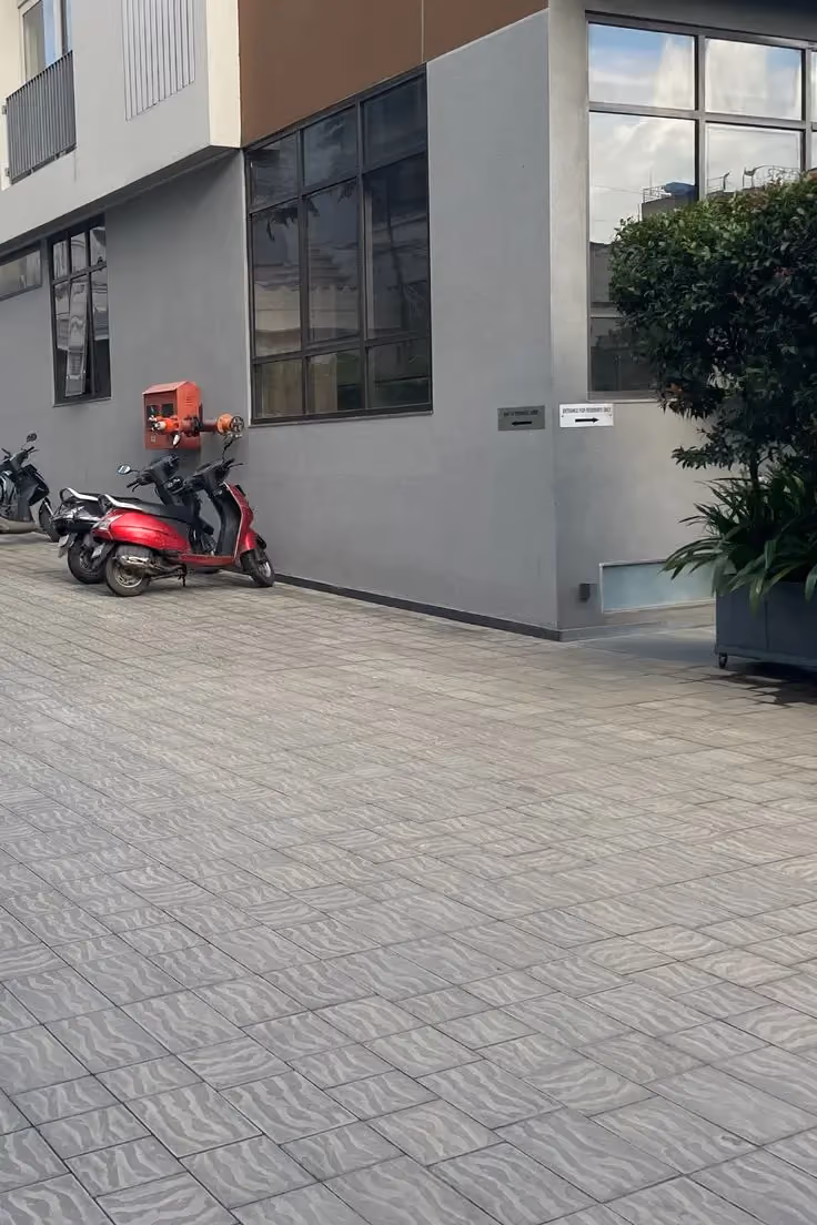 Grey Toscana pavers on a residential driveway and parking area beside a modern building with parked scooters