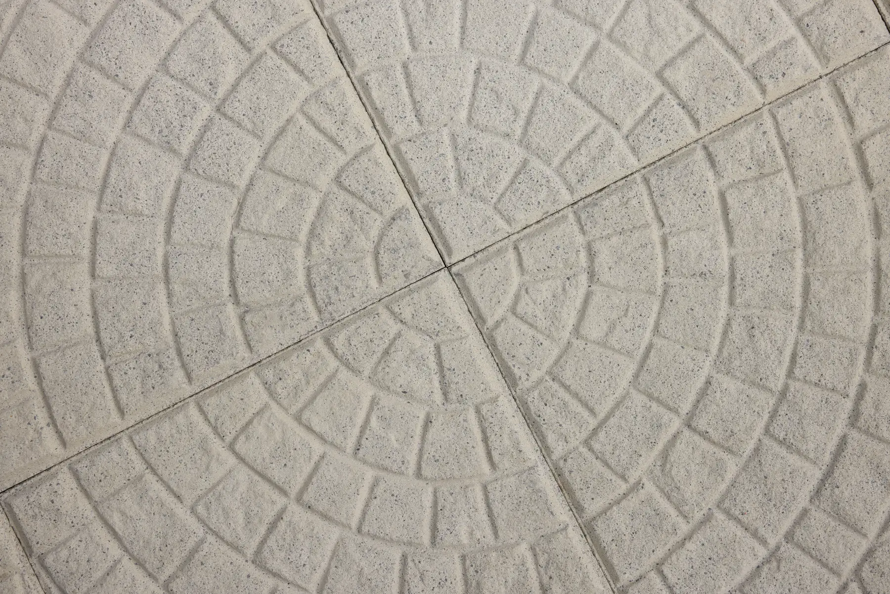 Close-up of light grey Ring Pattern concrete paving tiles forming concentric circles with a cobblestone-like texture
