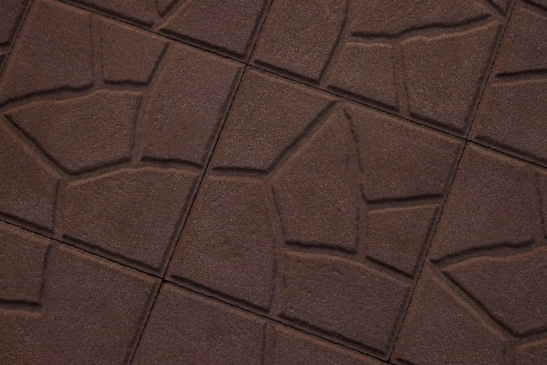 Close-up of brown Crazy Pattern square concrete paving tiles with irregular stone-like segments and a fine, grainy texture