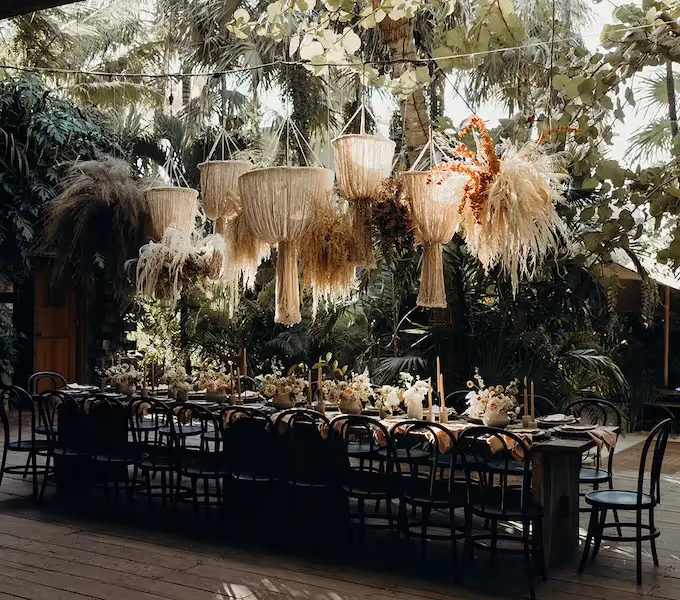 Mesa larga para recepción de bodas con decoración boho-chic, luces colgantes de paja y arreglos florales secos en el hotel La Valise Los Cabos.